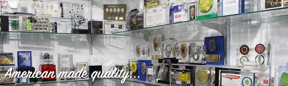 Multiple acrylic awards displayed on glass shelving.